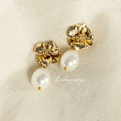 two pearls are sitting next to each other on a piece of white fabric with gold accents