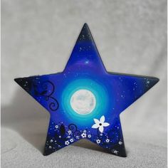 a blue glass star with white flowers on it and a full moon in the background