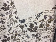 the fabric has many flowers on it and is white with brown trim, along with other floral designs