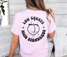 Low squats high standards peachy booty shirt. *Hot pink text goes on the black and white shirt colors only. Remaining shirt colors will receive black or white text.* UNISEX SHIRT 100% USA cotton Pre-shrunk so no need to worry about shrinkage Comfort Colors Brand Heavyweight material for a more comfortable fit Relaxed fit. Order a size up for a more baggy feel. Custom Gym Shirts, Trendy Pink Workout T-shirt, Workout Tshirt Design, Pink Short Sleeve Activewear With Letter Print, Pink Workout T-shirt With Letter Print, Pink Letter Print Workout T-shirt, Pink Letter Print T-shirt For Workout, Pink Relaxed Fit Short Sleeve Activewear, Pink Short Sleeve Relaxed Fit Activewear