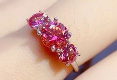 a close up of a person's hand with a pink diamond ring on it