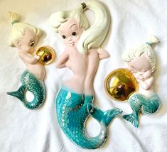 three little mermaid figurines sitting on top of a white sheet