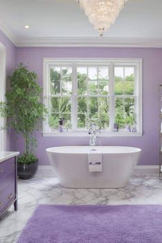 a white bath tub sitting under a window next to a purple rug in a bathroom