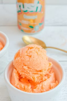 two white bowls filled with orange ice cream next to a can of yogurt