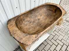 an old wooden bathtub sitting on top of a brick floor next to a white wall