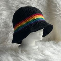 a white mannequin head wearing a black crochet hat with rainbow stripes