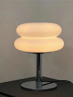 a lamp that is sitting on top of a black table next to a gray wall