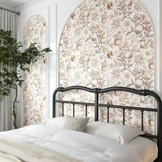 a white bed sitting under a window next to a potted plant