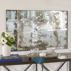 a table topped with a vase filled with white flowers next to a wall mounted mirror