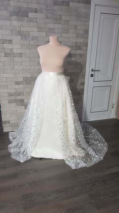 a white wedding dress on display in front of a brick wall and wooden flooring