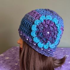 a woman's head wearing a purple and blue crocheted beanie hat