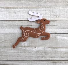 a felt reindeer ornament hanging on a wooden wall with white and brown trim