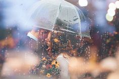 a woman standing under an umbrella in the rain with flowers on her head and hands