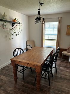 a dining room table with four chairs and a hanging potted plant on the wall