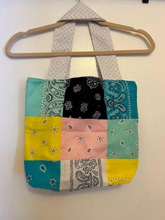 a multicolored patchwork purse hanging on a clothes hanger in front of a white wall