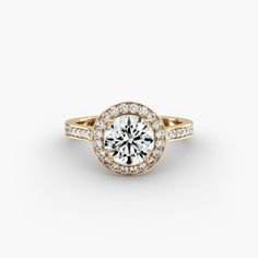 a yellow gold engagement ring with diamonds on the band and a round center stone in the middle