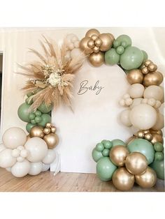 a baby shower is decorated with balloons and greenery in gold, green and white colors