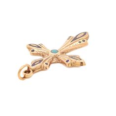 a gold dragonfly charm with blue stones on it's back end, sitting on a white surface