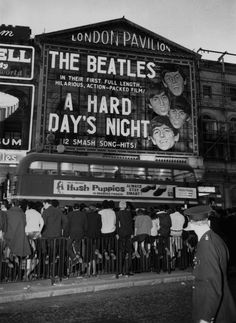 an old black and white photo of people standing in front of the beatles concert sign