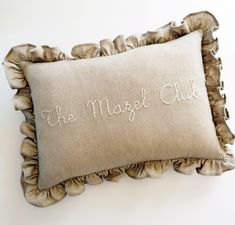 a decorative pillow with the words the most club embroidered on it and ruffled edges