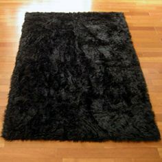 a black shaggy rug sitting on top of a hard wood floor