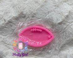 a pink football shaped plastic toy on a gray fur covered surface with a tag attached to it