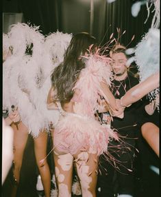 two women dressed in pink and white are dancing with feathers on the dancefloss