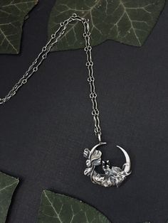 "Moon Garden | Art Nouveau, Crescent Moon Necklace, Antique Reproduction, Sterling Silver, Spinel, Oxidized, Witchy This lunar jewel, the first of my line of cast sterling silver moon metal jewels, is an ode to the beauty and romance of the Art Nouveau era that juxtaposes perfectly with Wyther's signature dark botanical aesthetic. Ivy leaves and vines with a flower in full bloom wind their way around this design. Cast from a 100+ year old antique brooch and modified to suit modern needs, including the addition of a basket setting that cradles within it a luminous 3mm Black Spinel faceted gemstone.  Moon measures 25mm or 1 inch approximately.  Individually cast and hand finished, with each protective black stone hand set by me. Intentionally made from solid sterling silver moon metal that h Handmade Moon Shaped Nature-inspired Necklace, Nature-inspired Moon Charm Pendant Necklace, Artisan Moon Charm Necklaces, Silver Moon-shaped Nature-inspired Jewelry, Nature-inspired Sterling Silver Moon Charm Jewelry, Collectible Moon Charm Pendant Necklace, Unique Moon-shaped Engraved Necklace, Nature-inspired Silver Moon Shaped Jewelry, Nature-inspired Silver Moon Jewelry