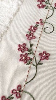 a close up of a piece of cloth with flowers on it and thread in the middle