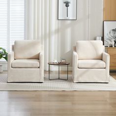 two white chairs sitting next to each other in a living room