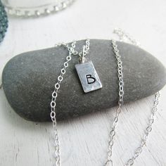 Sterling silver keepsake necklace. Small tag charms are textured and stamped with the letters that mean the most to your heart. Add your initials in the order notes box at checkout. Solid sterling silver charms 1/4 wide and 1/2 longSterling silver cable chain. Adjustable Stamped Sterling Silver Charm Necklaces, Adjustable Sterling Silver Stamped Charm Necklace, Silver Pendant Charm Necklace Stamped, Hand Stamped Sterling Silver Rectangular Necklaces, Silver Stamped Rectangular Pendant Necklace, Keepsake Necklace, Light Grid, Sterling Silver Charms, Sterling Silver Charm