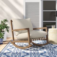 a rocking chair sitting on top of a blue rug next to a potted plant