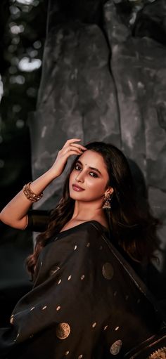 a woman in black sari posing for the camera with her hand on her head