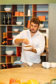 a man standing in front of a counter with bowls and plates on top of it