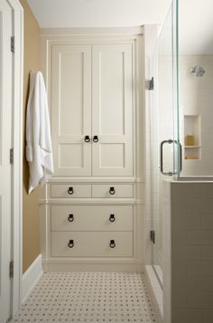 a white bathroom with black handles and drawers