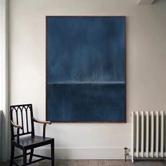 a painting hangs on the wall next to a chair and radiator