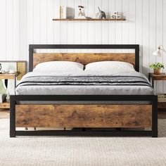 a bed that is made up with wood and metal frame, in a white room