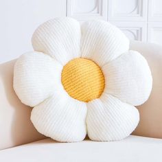 a white couch with a yellow and white flower on it's backrests