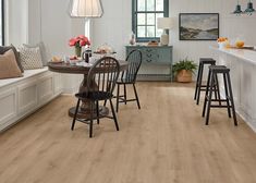 a kitchen with white walls and wood flooring is pictured in this image, there are four chairs around the table