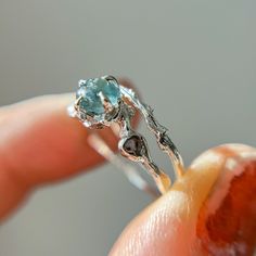 a close up of a person's hand holding a ring with an aqua stone