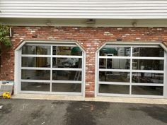 two garage doors are open in front of a brick building with windows on each side