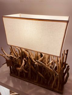 a table lamp made out of driftwood on top of a wooden stand with a white shade over it