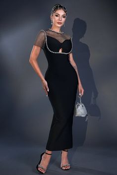 a woman in a black dress with sheer sleeves and pearls on her head, posing for the