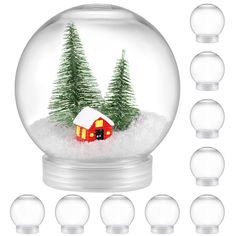 a snow globe with christmas trees and a red house in the middle surrounded by glass balls