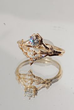 two gold rings sitting on top of each other, one with a diamond in the middle