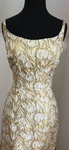 This dazzling 1950s metallic gold and white floral brocade wiggle dress is absolute perfection as a vintage wedding dress.  The metallic thread is perfect for a formal ocassion. Get your perfect hourglass figure with it's nipped-in waist and graceful open decolletage.  The "pencil skirt" cut of the bottom half of this dress slims and lengthens the legs while it emphasizes the feminine form of your hips - dangerous curves ahead!  For your mid-century themed wedding this dress is a MUST!  Why not be a bombshell!? Dimensions Bust: 37" Waist: 28" Hip: 38" Length: 39" White And Gold Cocktail Dress, 50s Wiggle Dress, Formal Gold Brocade Dress, Fitted Vintage Gold Dress, Gold Fitted Vintage Dress, Vintage Fitted Gold Dress, Vintage Brocade Fitted Dress, Fitted Vintage Brocade Dress, Gold Cocktail Dress