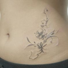 a woman's stomach with a flower tattoo on the side and an arrow in the middle