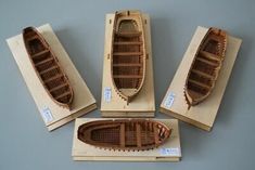 four wooden boats sitting on top of each other next to boxes with tags around them