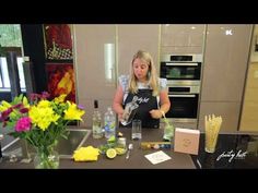 a woman in an apron preparing food on a kitchen counter with flowers and lemons