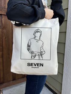 a woman holding a tote bag with the words seven on it